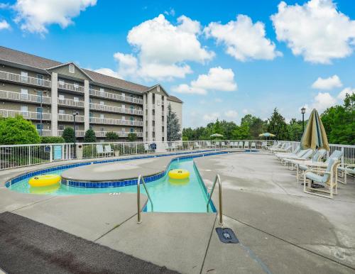 a swimming pool with chairs and a building at Rock-a-While Whispering Pines 214 in Pigeon Forge