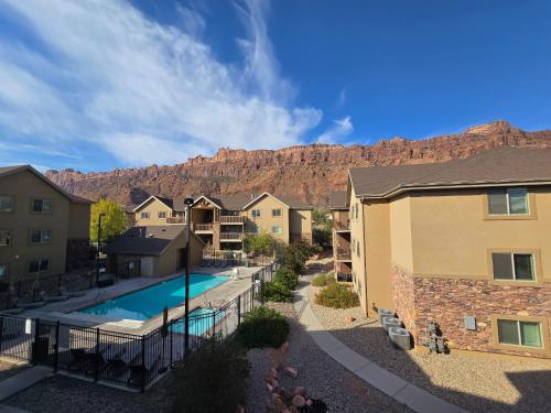 an apartment complex with a pool and mountains in the background at Red Cliff Condos #3i in Moab