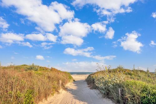 a dirt road leading to a beach under a cloudy sky at Crandalls Cottage in Port Aransas