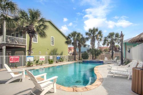 a swimming pool with white chairs and a green house at Sandy Starfish in Port Aransas