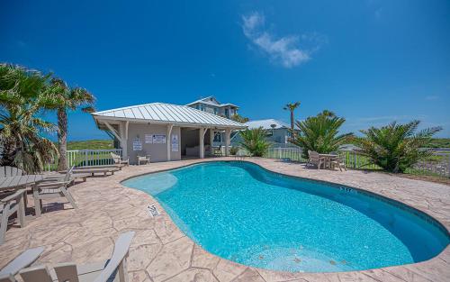 a swimming pool with chairs and a house at Postcard from Paradise in Padre Island