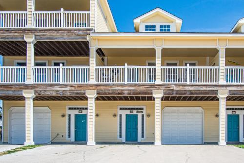 a large house with blue doors and a balcony at 3 Sheets To the Zin in Port Aransas