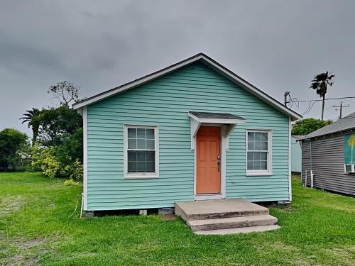 a blue house with a red door in a yard at Coral Cottage in Rockport