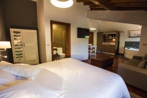 a bedroom with a large white bed and a living room at Casa Rural Arregi in Oñati