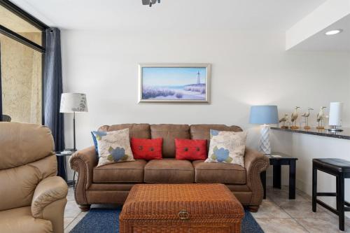 a living room with a brown couch and red pillows at Laguna Reef #315 - Bayview Retreat in Rockport