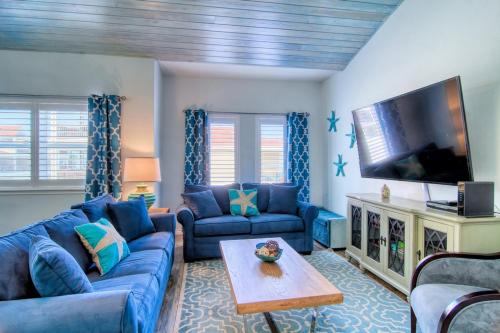 a living room with blue couches and a flat screen tv at Flip Flops & Pop Tops in Port Aransas