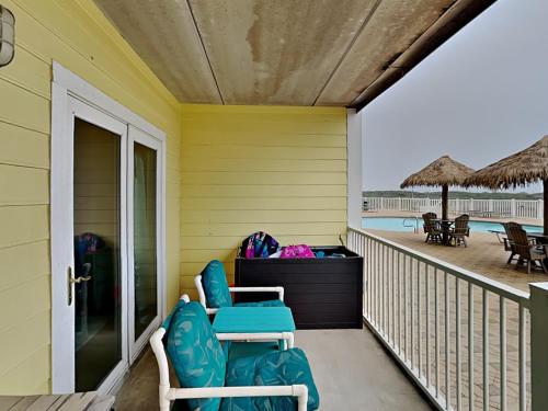 a porch with chairs and tables on the beach at Port A Condo in Port Aransas