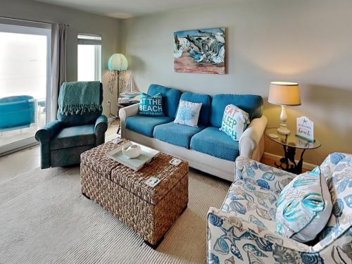 a living room with a blue couch and two chairs at Port A Condo in Port Aransas