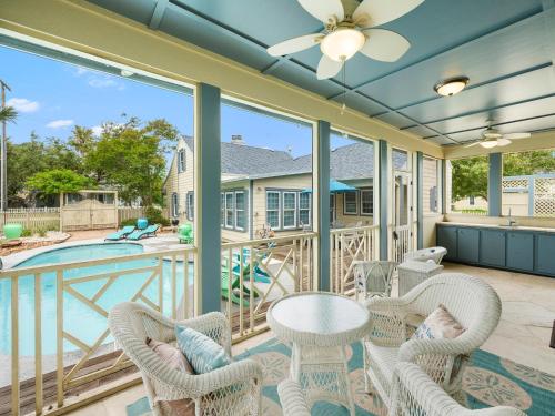 a screened porch with chairs and a table and a pool at Magnolia Cottage in Rockport