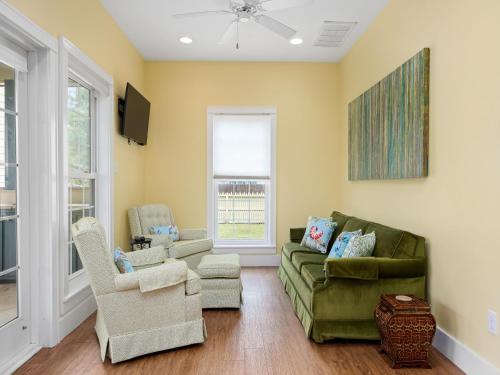 a living room with a green couch and chairs at Magnolia Cottage in Rockport