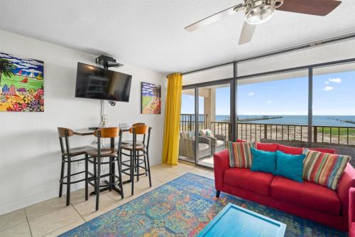 a living room with a red couch and a table with a bar at Laguna Reef #215 - Tequila Sunrise in Rockport