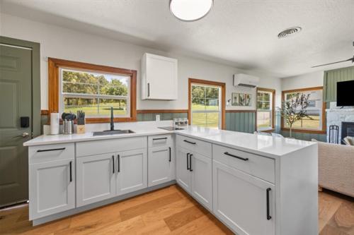 a large kitchen with white cabinets and a counter top at Willow Heaven - Lakefront Cabin Escape in Madill