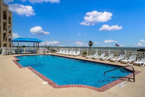 a swimming pool with chairs and the ocean in the background at Laguna Reef #121 - Gone Coastal in Rockport
