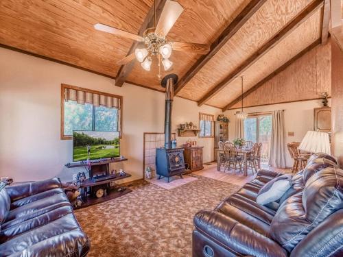 a living room with a leather couch and a television at Mockingbird Cabin in Ruidoso