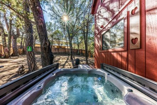a hot tub in front of a red building with trees at Mockingbird Cabin in Ruidoso