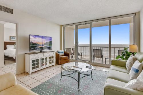 a living room with a couch and a tv at Galvestonian 1002-Beachfront Getaway in Galveston