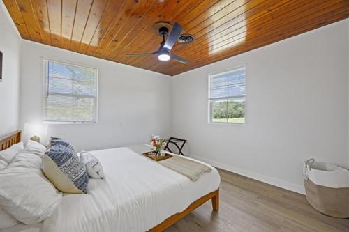 a bedroom with a bed with a ceiling fan at Whispering Oak- Lakefront Cabin Retreat in Madill