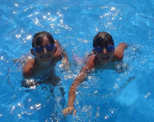 twee jonge jongens met een zonnebril in een zwembad bij Hotel Miramare in Bibione