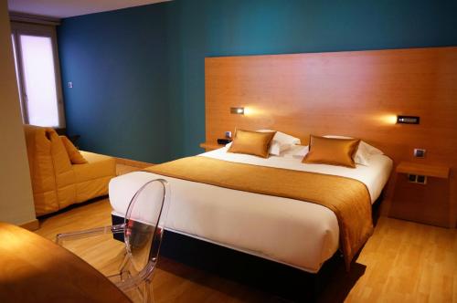 a bedroom with a large bed and a chair at LOGIS Hôtel de Bourgogne - Mâcon in Mâcon