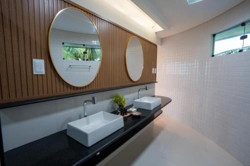 a bathroom with two sinks and two mirrors at Mansao in Maragogi