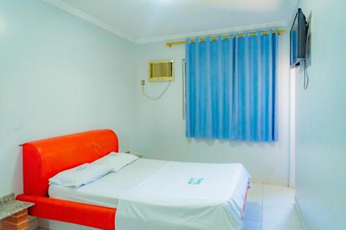 a red bed in a room with a blue curtain at Hotel Oliveira in Goiânia