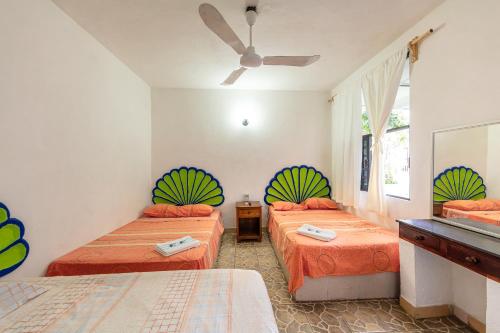 a bedroom with two beds and a ceiling fan at Hotel Naxhiely in Puerto Escondido