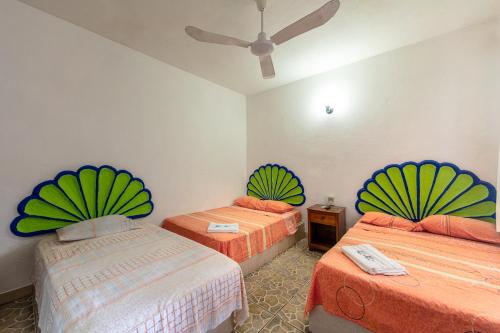 a bedroom with two beds with green and orange at Hotel Naxhiely in Puerto Escondido