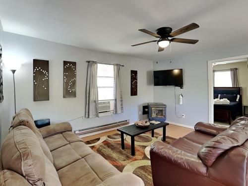 a living room with a couch and a ceiling fan at Knotty Pines Cabin in Ruidoso