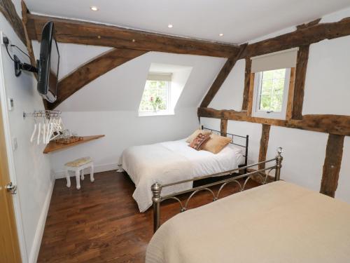 a attic bedroom with two beds and a tv at Lower Tundridge Cottage in Suckley