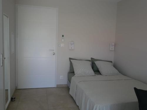 a white bedroom with a bed with two pillows at Studios Saint Mau 3 in Saint-Maurice-de-Gourdans