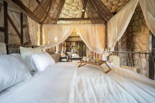a bedroom with a large white bed with curtains at Maison Lakala in Ben Slimane