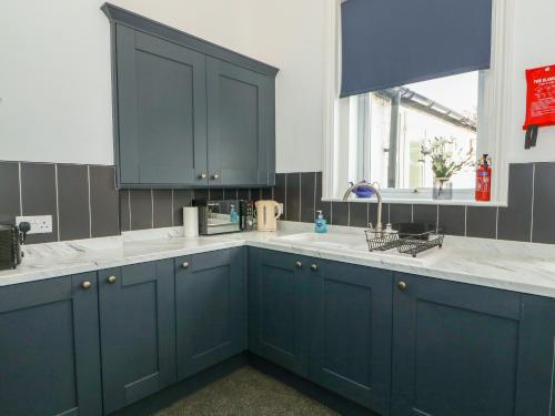 a kitchen with blue cabinets and a sink at Northgate Ground Floor Flat in Hunstanton