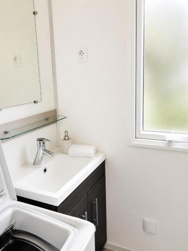 a white bathroom with a sink and a mirror at Feel MH 54 in Gastes