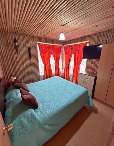 a bedroom with a bed with red curtains and a television at Hospedaje Naomi in Valparaíso
