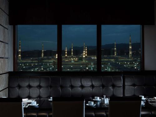 a restaurant with a view of a city from a window at Zamzam Pullman Madina in Medina