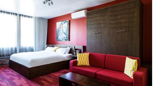 a hotel room with a bed and a red couch at C3- Hotel Art De Vivre in Quebec City