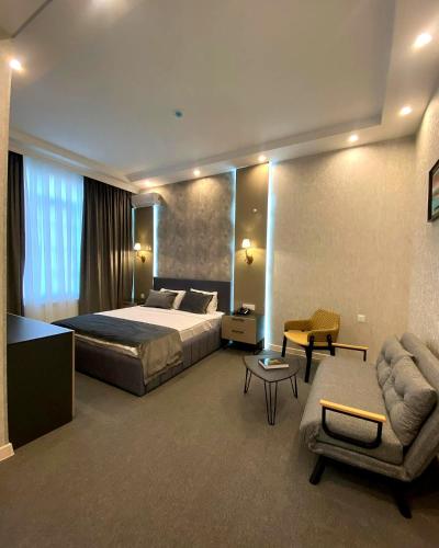 a bedroom with a bed and a couch and a chair at Northern City Hotel in Zaqatala