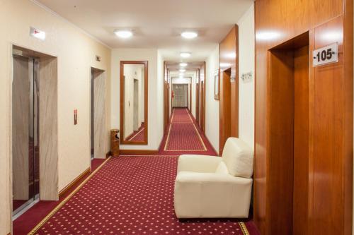 a hallway with a white chair and a red carpet at Hotel Bella Vista in Drvenik