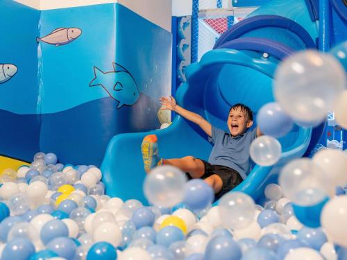 a young boy is sliding down a tunnel of balls at Novotel Phuket Kata Avista Resort and Spa in Kata Beach