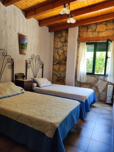 a bedroom with two beds and a stone wall at Casas Rurales Ribera de Salobre in Salobre
