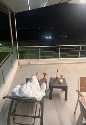 a man laying on a chair with a glass of wine at AMORÉA Jacuzzi Suites Evia in Eretria