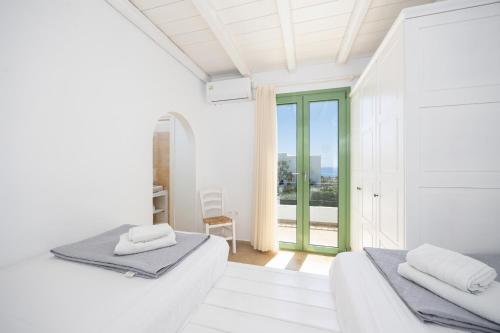 a white room with two beds and a balcony at Villa Loka in Gennadi
