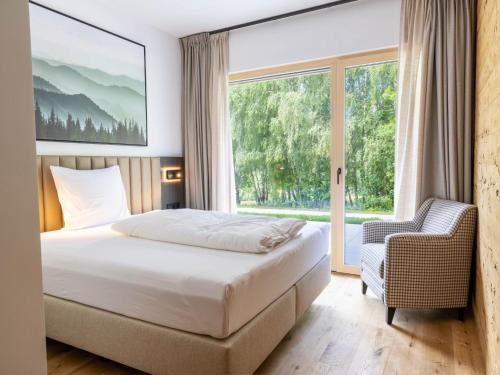 a bedroom with a bed and a window and a chair at Dachstein Grand Alpine Lodge in Mitterberg-Schladming-Dachstein