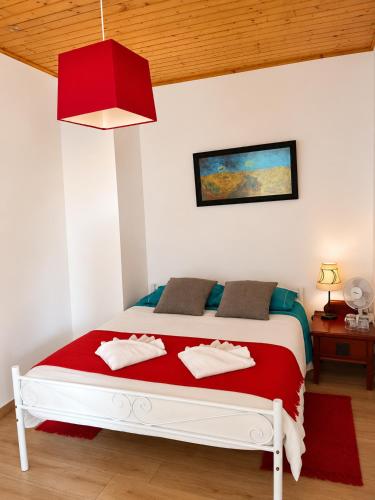 a bedroom with a white bed with a red blanket at Casa da Prainha 4 in São Caetano
