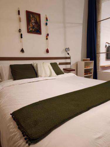 a bedroom with a white bed with a green blanket on it at KANTIQ House in Cusco
