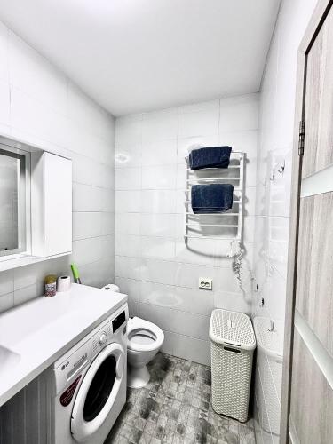 a white bathroom with a toilet and a sink at Apartment Synergia 3 in Irpin