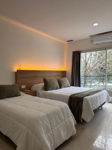 two beds in a hotel room with a window at Aparts Magallanes in Pilar