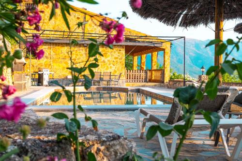 a yellow building with a pool and chairs and flowers at El Valle Dorado in El Gastor