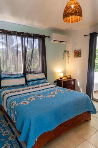 a bedroom with a bed with a blue comforter and a window at Kassuky Home in Cabarete