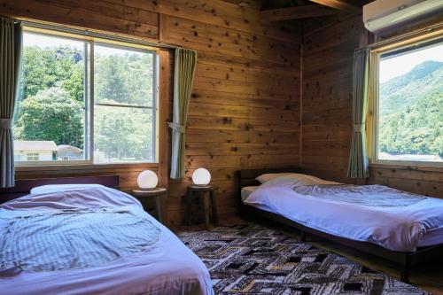 two beds in a wooden room with two windows at Koguchi Village by WhyKumano in Shingū